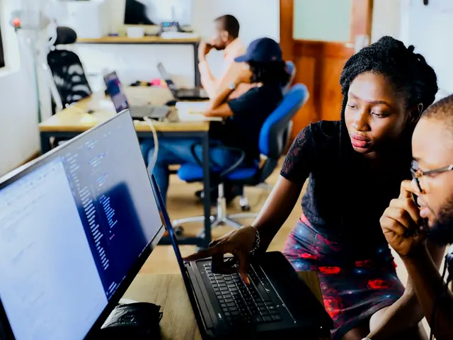 Two colleagues reviewing work together on a laptop
